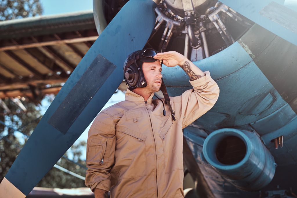 Young pilot is standing near his jet.
