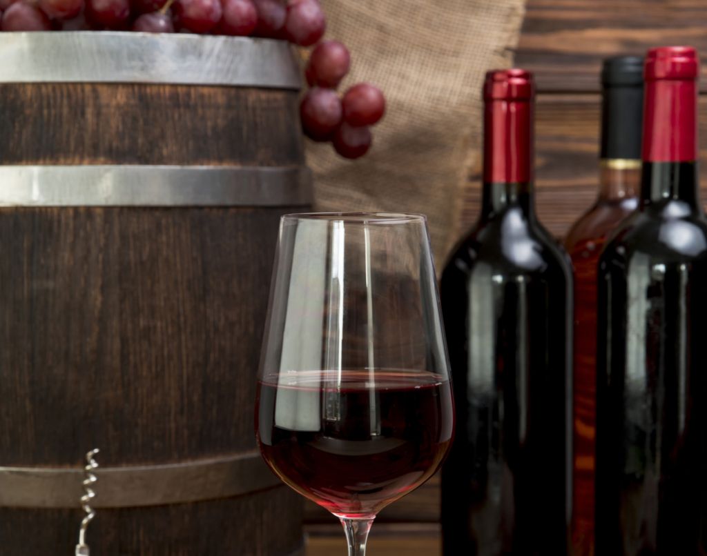 hand-holding-glass-wine-with-bottles-barre